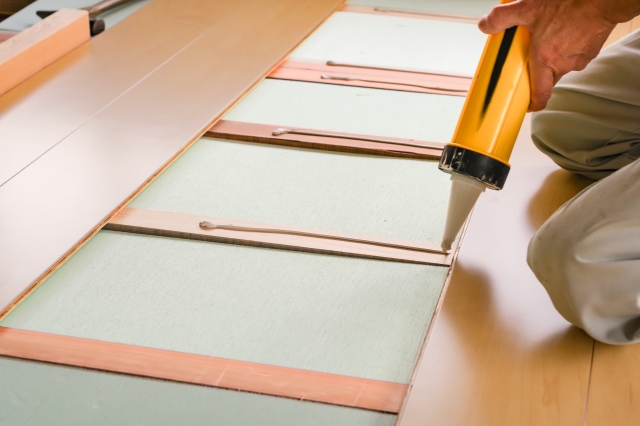 接着剤でフロア材を張るシーン。